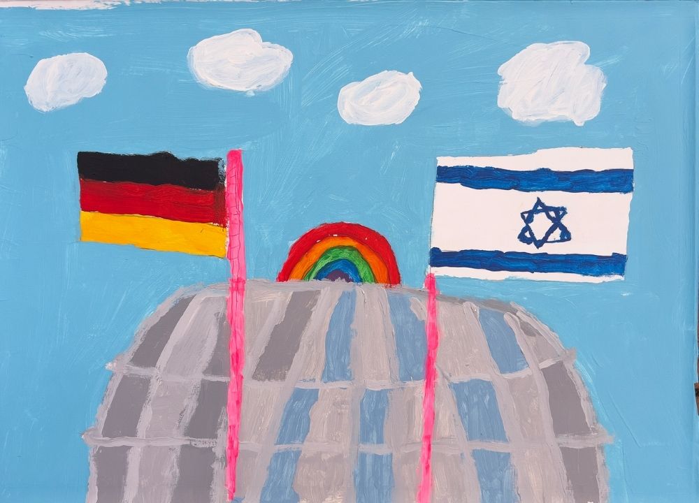 In the foreground of the painting, a building in the shape of a round glass dome is depicted. Above it is a small, colorful rainbow. In front of it are two flagpoles, each with a German flag and an Israeli flag. The background is the blue sky and four wispy clouds.