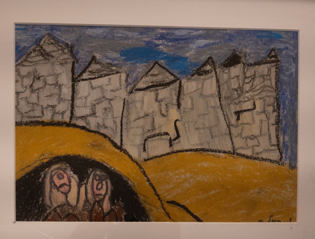 The foreground shows two people hidden in a cave. In the background, city buildings are suggested.
