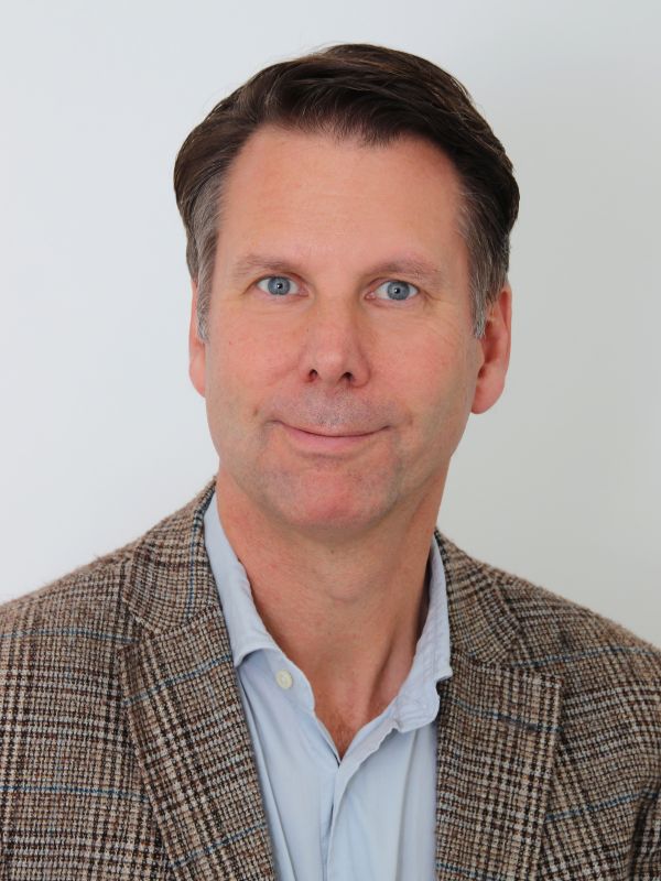 Nils Wöbke A man with short brown hair wears a light blue shirt and a checked jacket